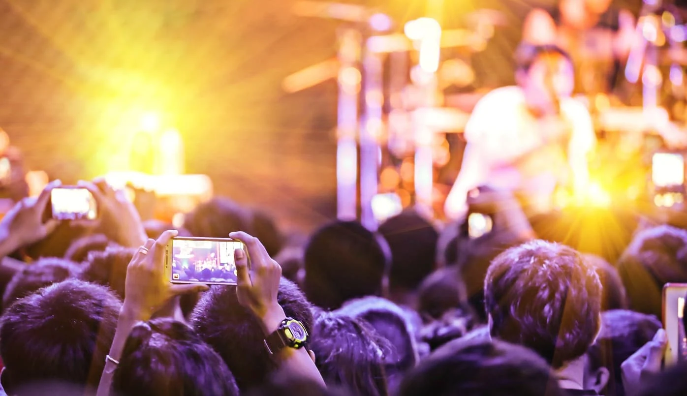 Event goers film a performance on their mobile phones.